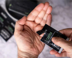 A person adding a sample pack of Canyon-scented beard oil to their palm.